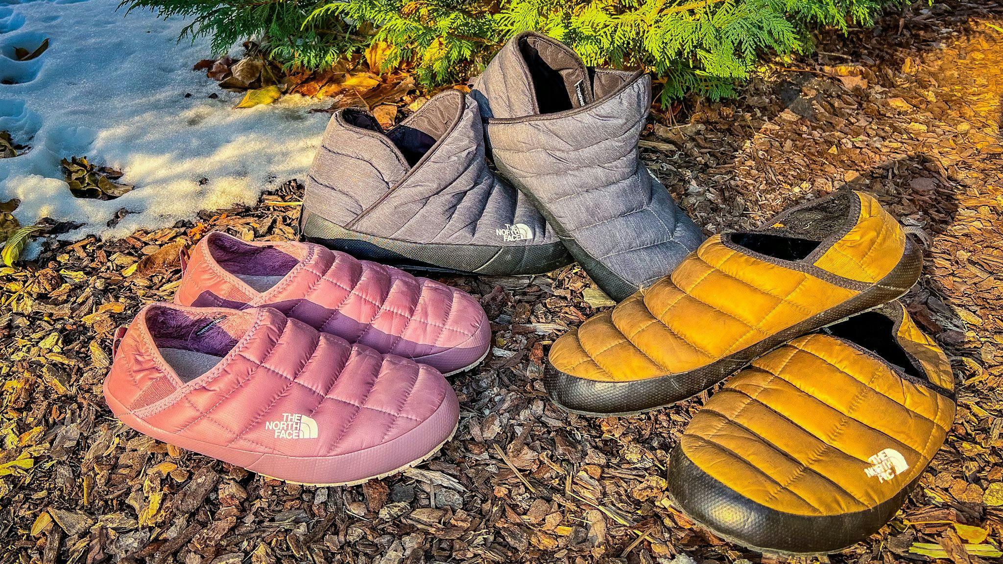 2 pairs of different colored thermoball camp slippers on display at campsite.