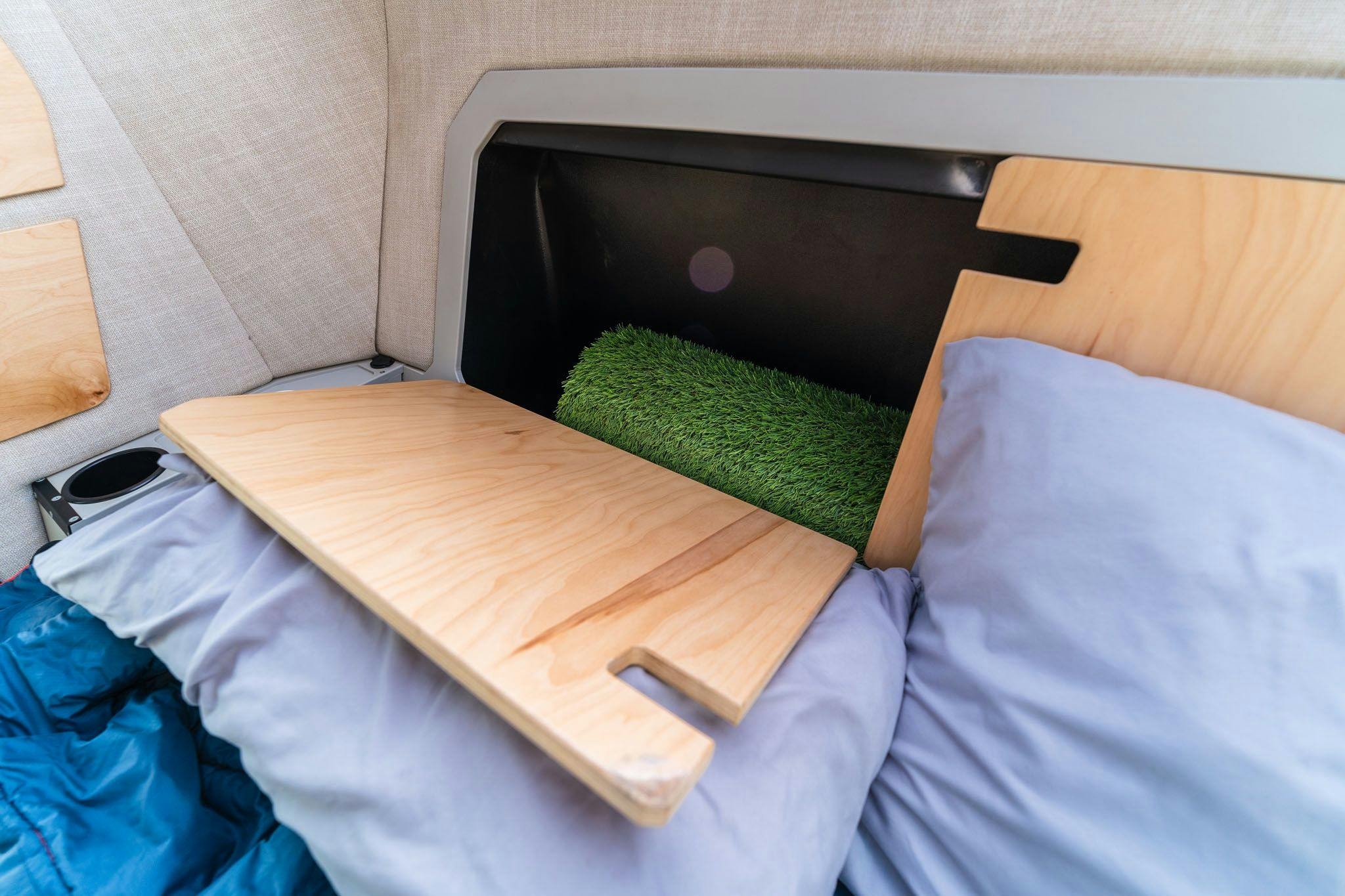 In the cabin of the TOPO2, an offroad trailer, the headboard has two panels that fold down to reveal additional storage space.