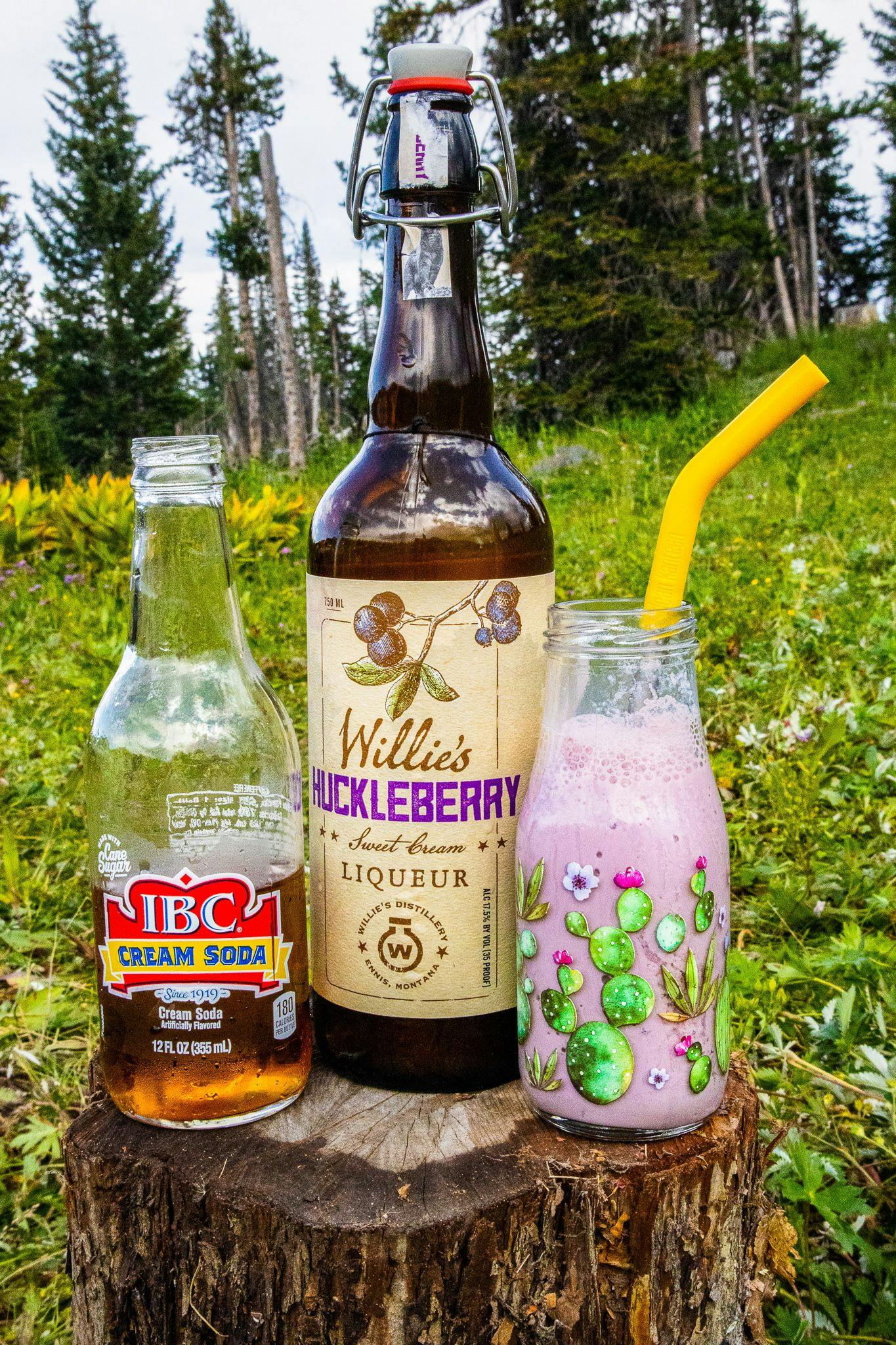 The ingredients for a huckleberry cocktail posed on a stump.