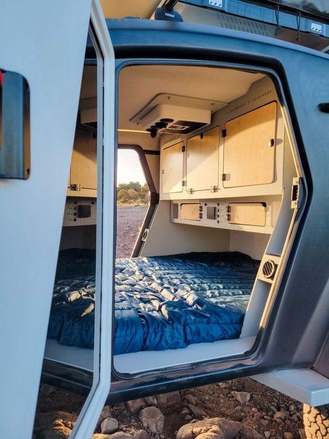The sun dances into the interior of a teardrop camper, creating a warm cozy vibe.
