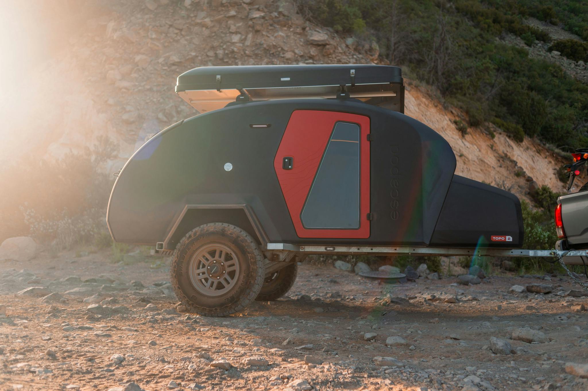 A teardrop camper with a rooftop tent mounted on top.