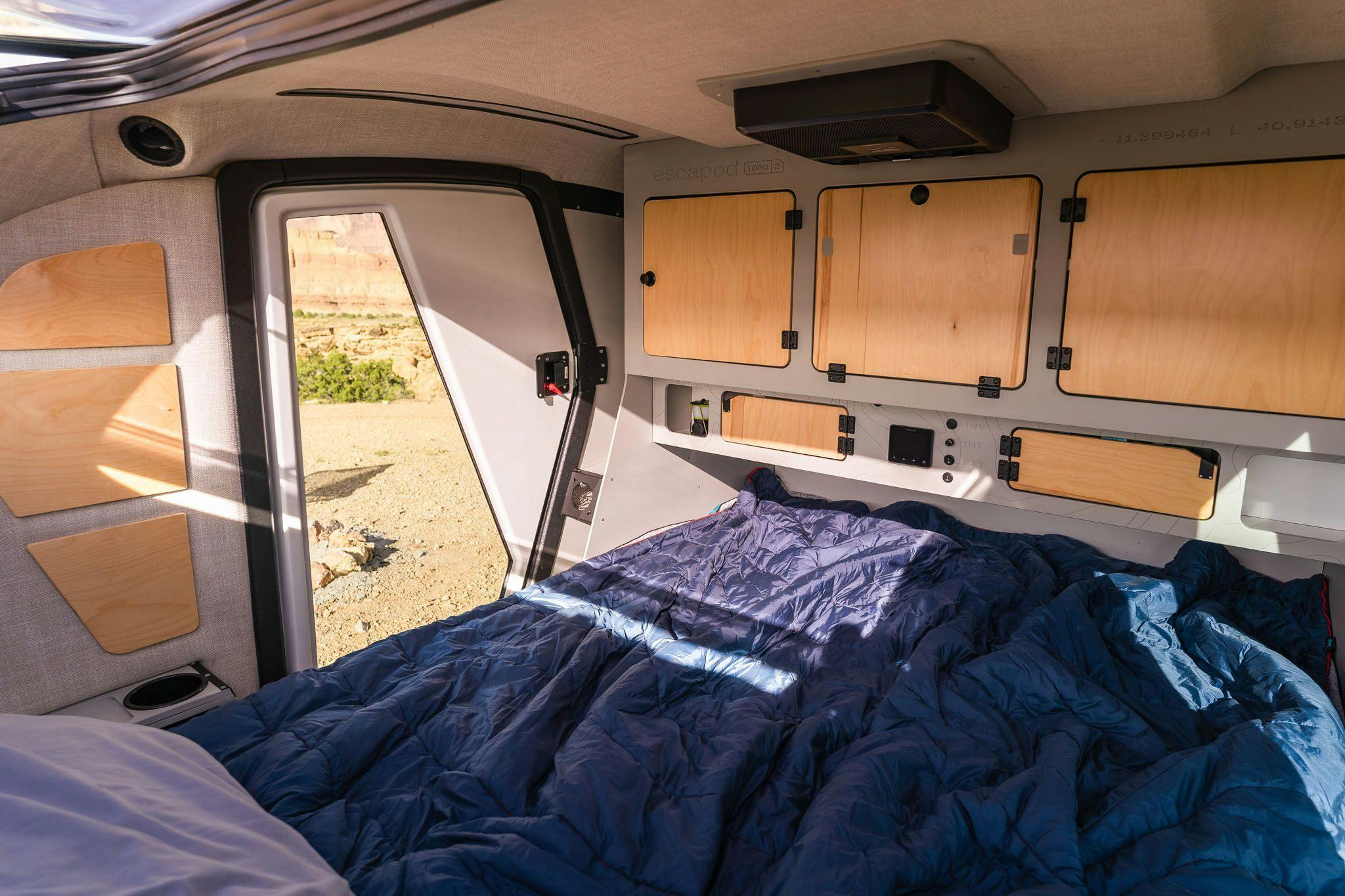 The interior of the TOPO2, a teardrop trailer, with a true queen mattress, cabinets for storage, and more.