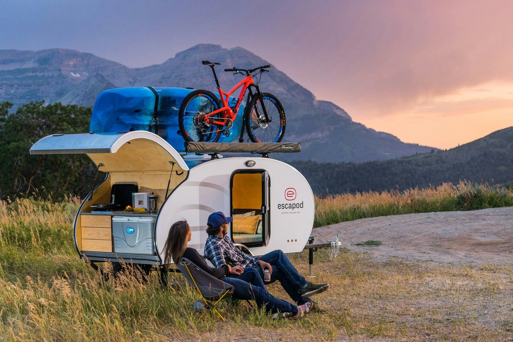 Co-founders of Escapod, Jen & Chris, lounging with one of their original teardrop trailer builds enjoying mountrain views.