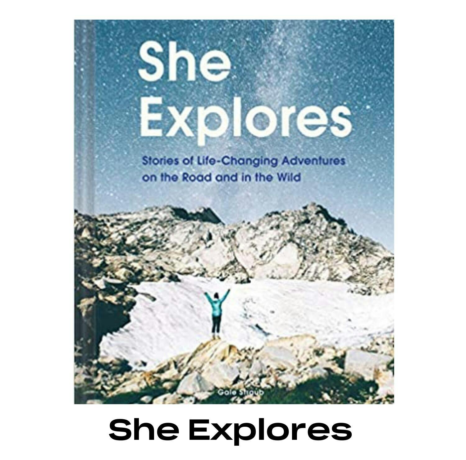 The cover of the "She Explores" book depicts a woman standing on top of a rock with her arms in the air in celebration.