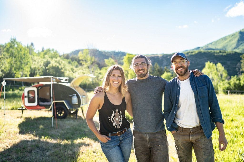 Image of three people in front of a teardrop camper.
