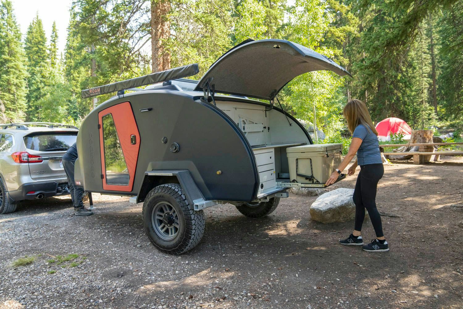 A woman pulling out the YETI cooler drawer slide in her camp kitchen of her adventure trailer.