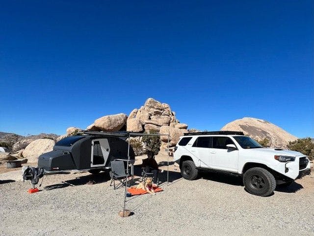 A storm grey TOPO2, an offroad adventure trailer hooked up to a Toyota 4Runner parked at a desert camping spot.