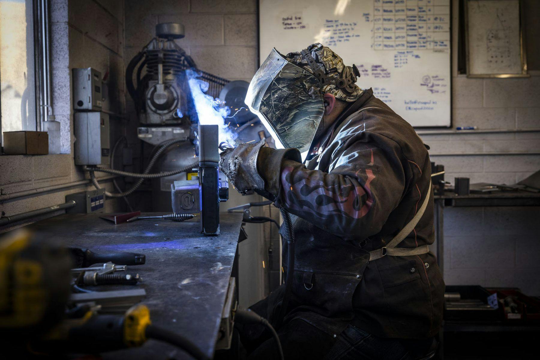 A welder working on a small teardrop trailer build.