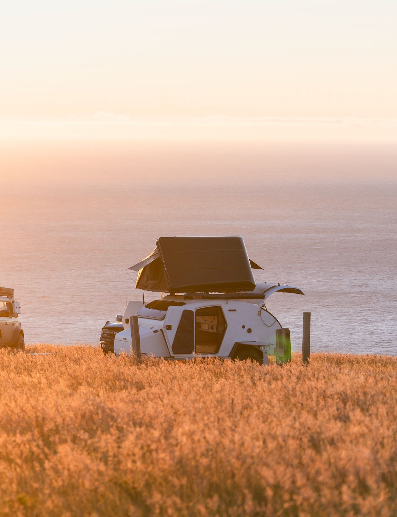 TOPO2 Voyager in a campsite overlooking the Pacific Ocean next to a Ford Bronco.