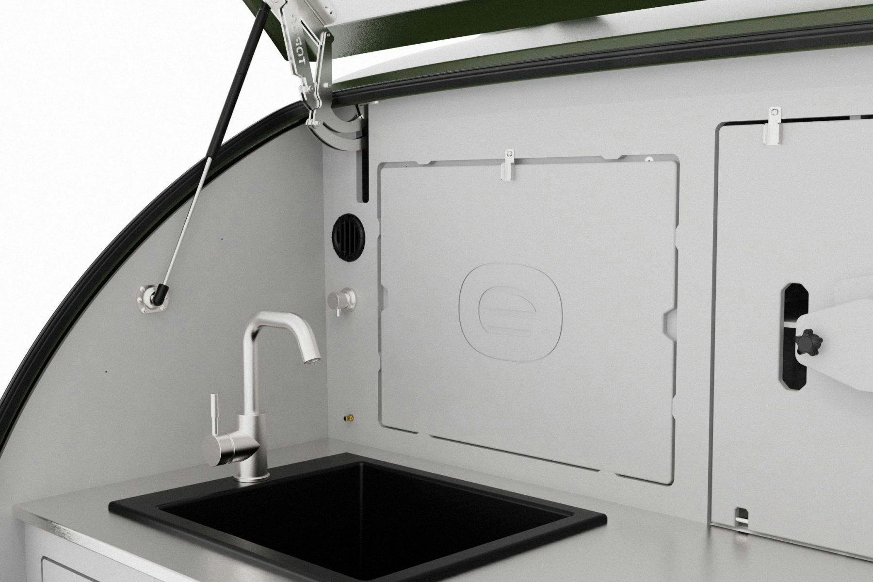 A light grey interior galley of a teardrop trailer, with a full sized sink and cutting board.