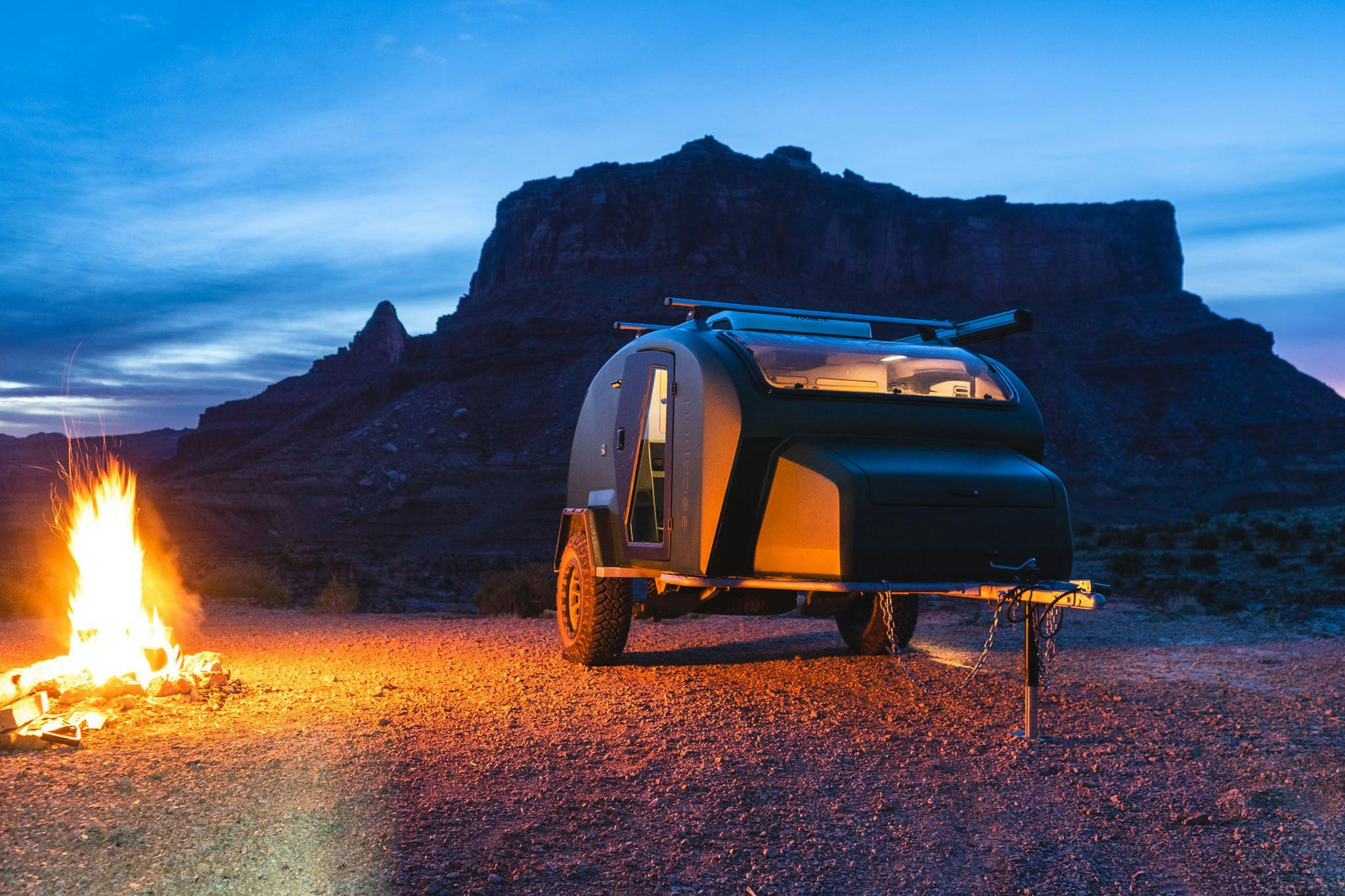 A Moss TOPO2, a custom adventure trailer by Escapod Trailer, parked in the San Rafael Swell lit up by the glow of a campfire.