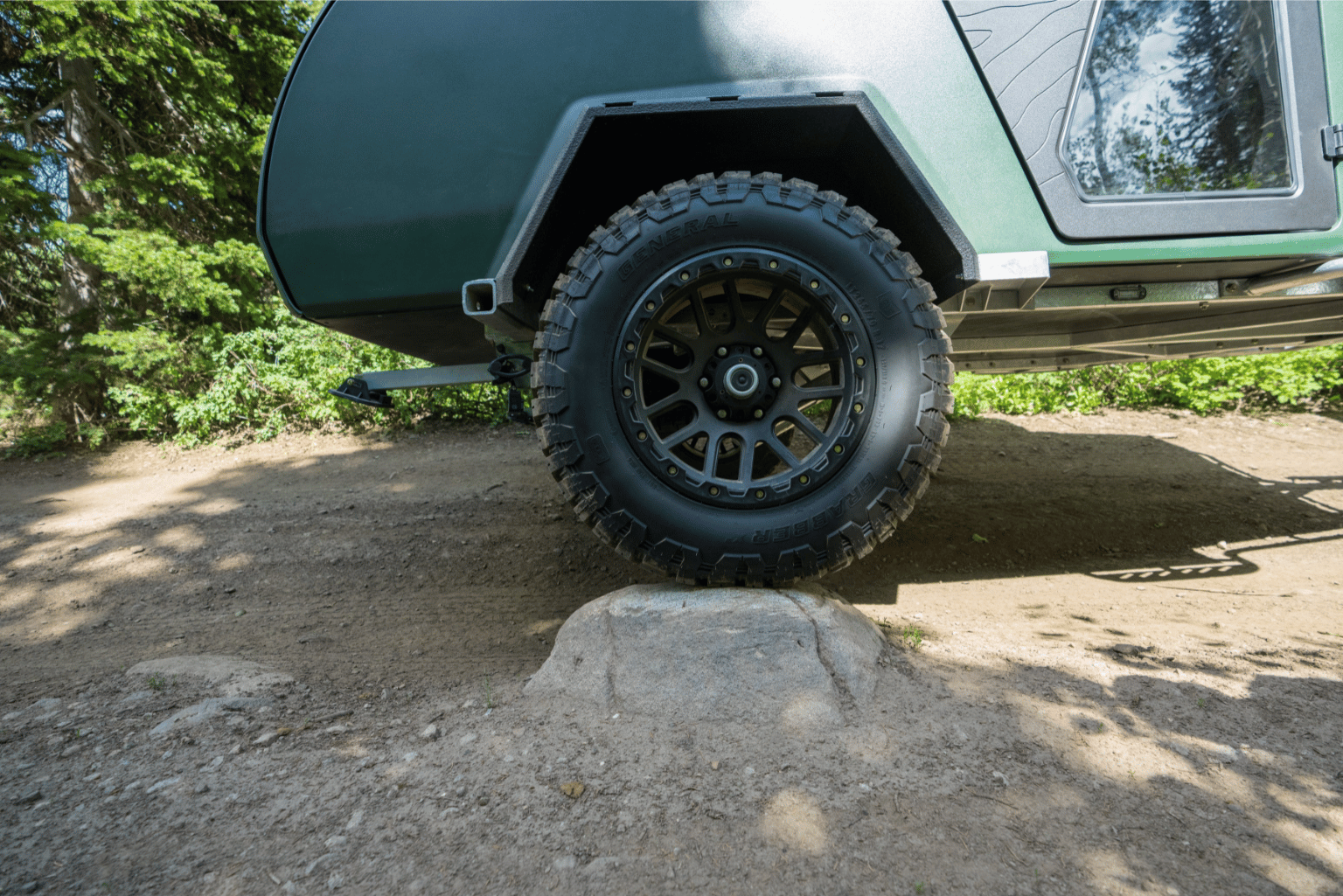 Offroad wheels and tires mounted on to a green teardrop trailer.