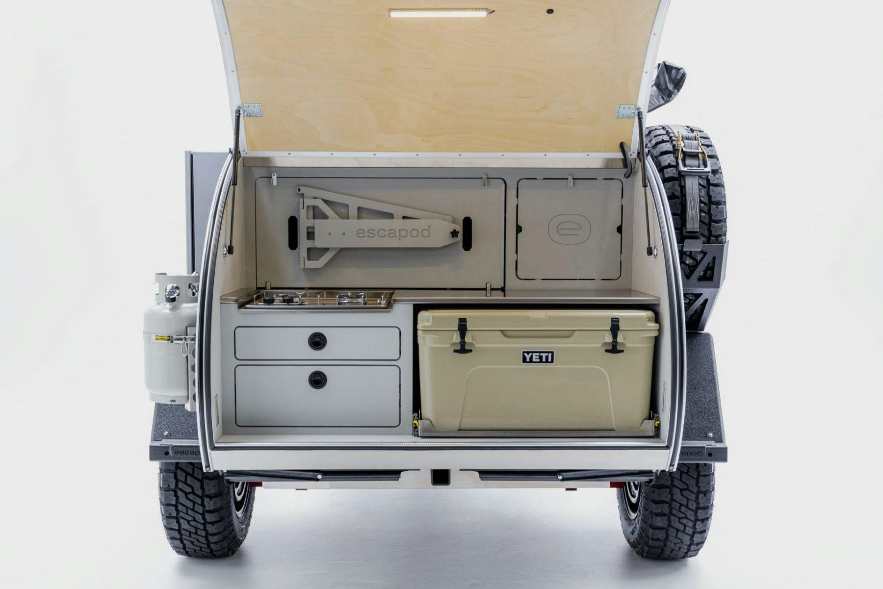 A galley shot of a teardrop camper, showing the storage, stove, and cooler.