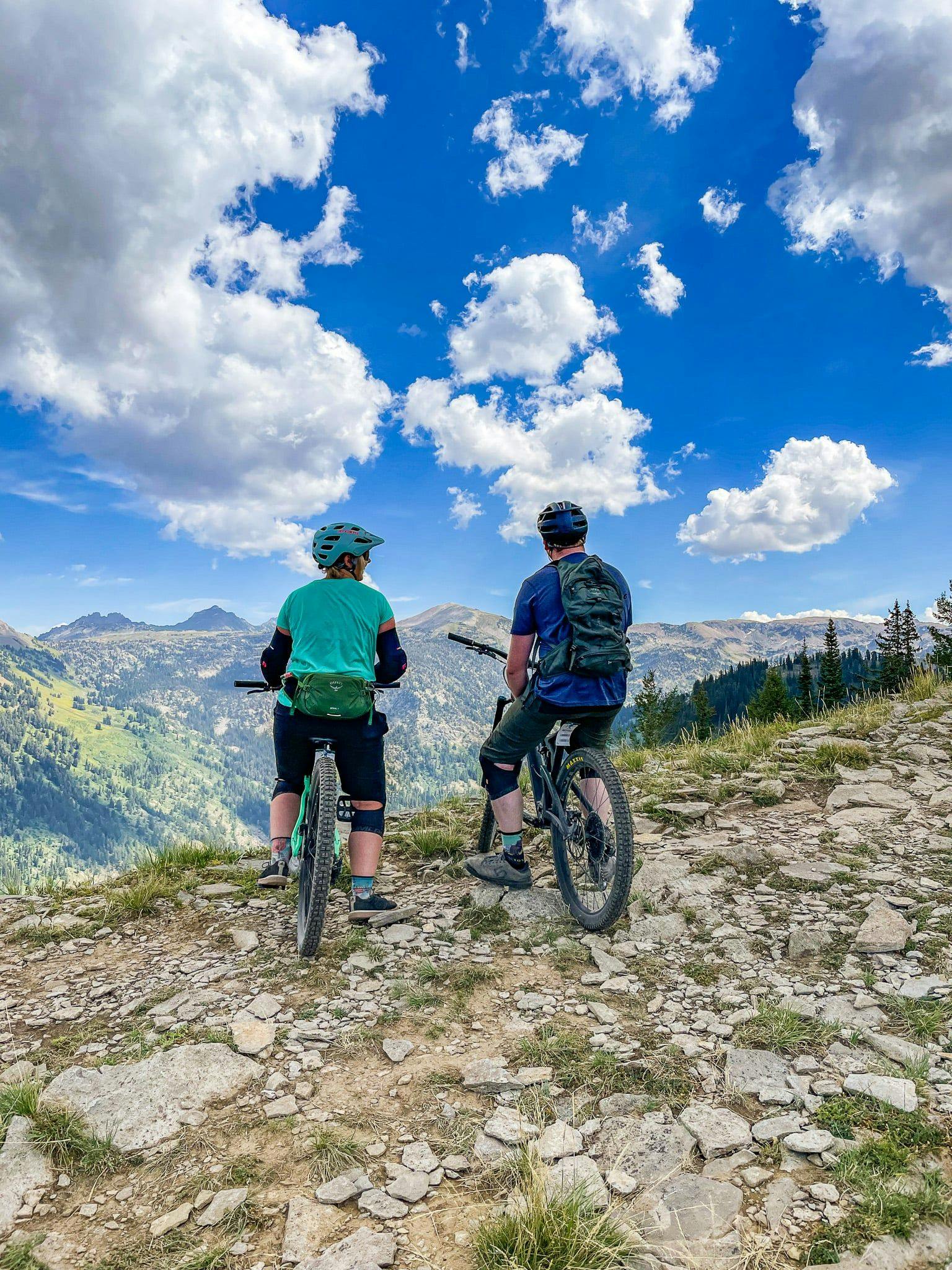 A couple mountain biking to some amazing outdoor views.