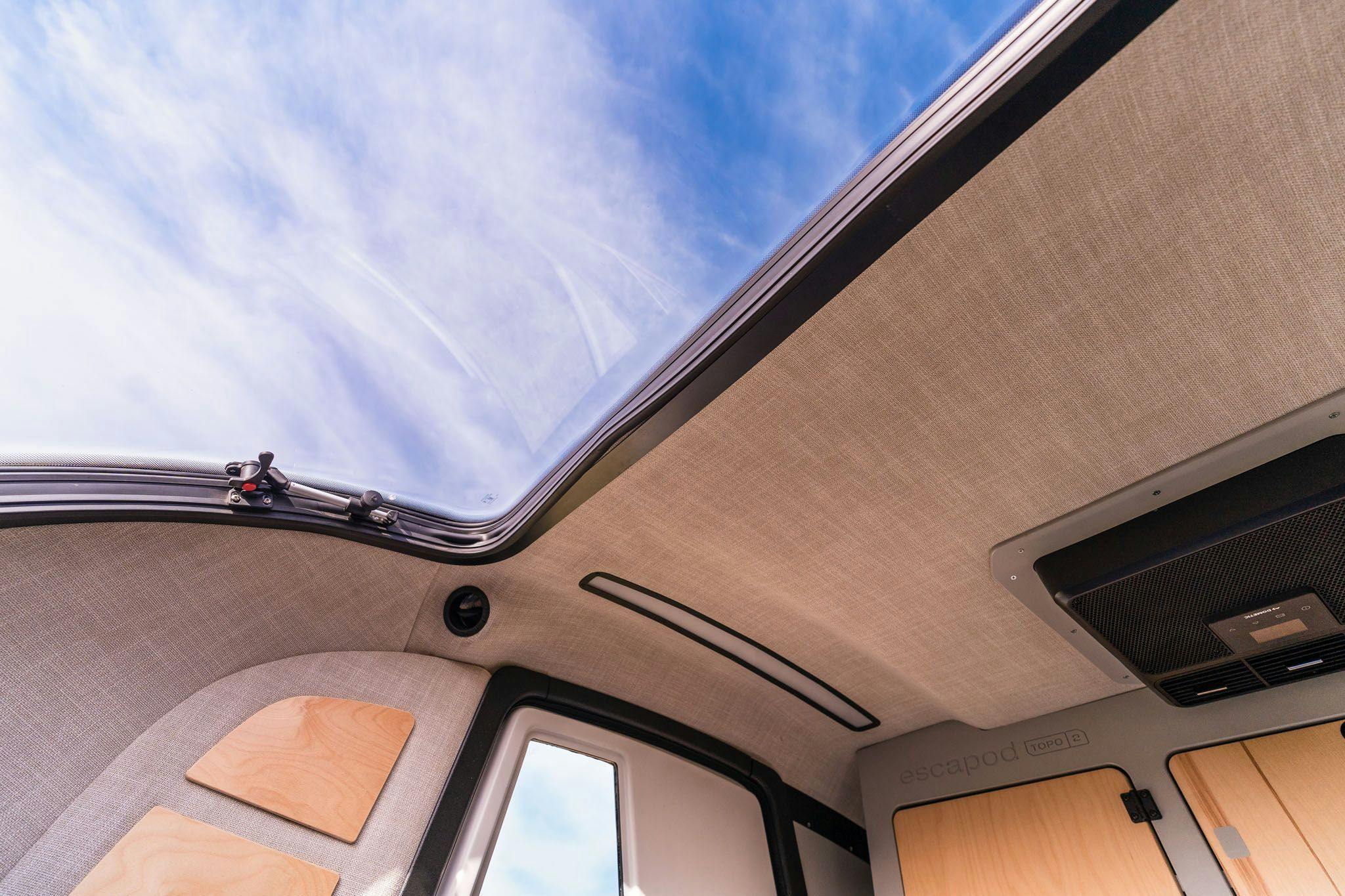 A stargazer window in the cabin of the TOPO2, a teardrop trailer, showing blue skies outside of the camper.
