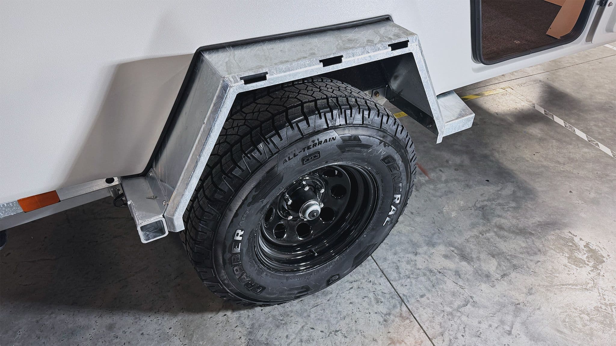 A detail shot of the Escapod TOPO2 Nomad steel Vision wheel and General ATP all terrain tire, inside a fully galvanized fender.